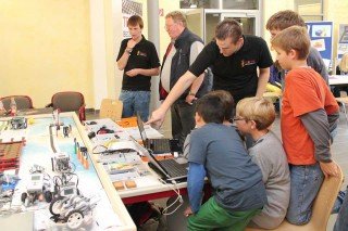 Praxistag Perspektive Technik in Unna am 14.09.2012: Jugendliche und erwachsene Besucher lassen sich von den ehemaligen Walburgisschülern die LEGO Robotertechnik erklären. (Foto: Technik begeistert)