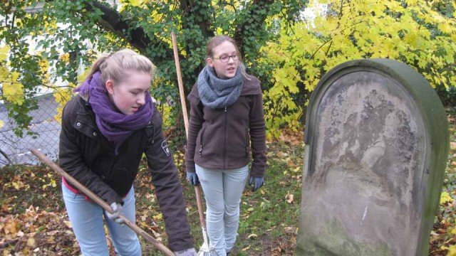 Schülerinnen der Klasse 7b des Walburgisgymnasiums säubern einen Grabstein auf dem Jüdischen Friedhof Menden. (Foto: WBG/Mertens)